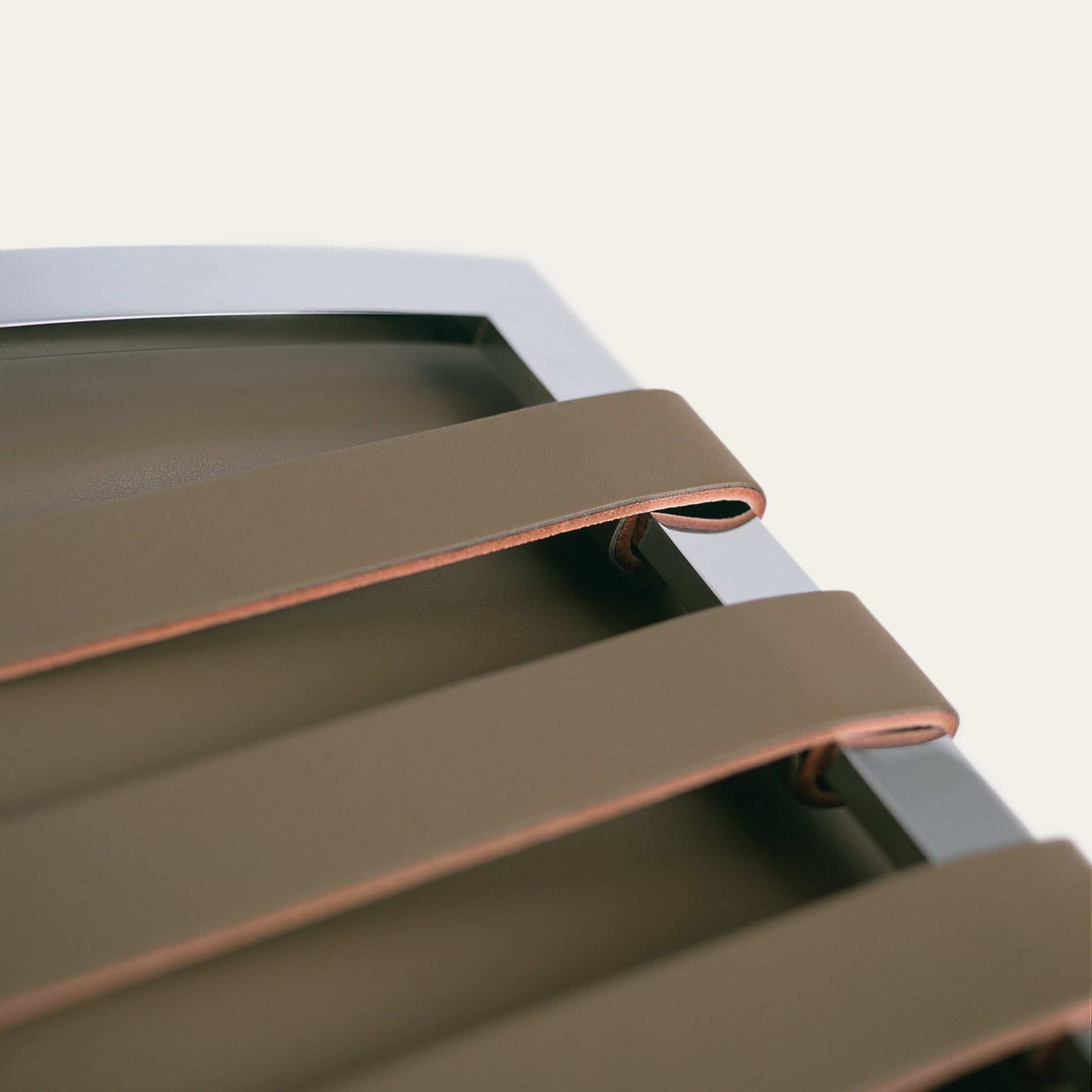 Detailaufnahme der Lederbänder unter dem Sitz des Barcelona Chairs, befestigt an einem verchromten Stahlrahmen