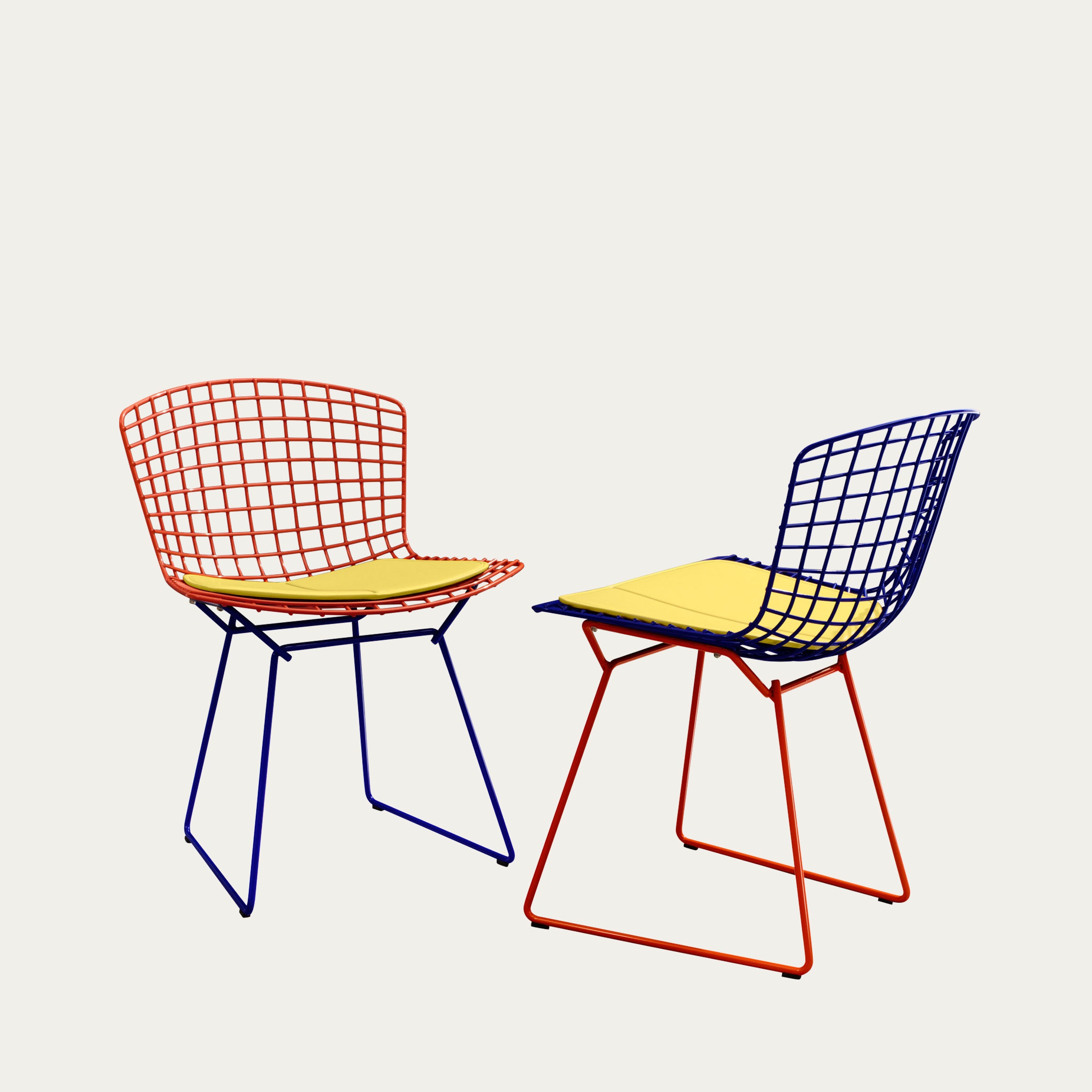 Zwei Bertoia Side Chairs aus Drahtgeflecht in Blau und Rot mit gelben Sitzkissen