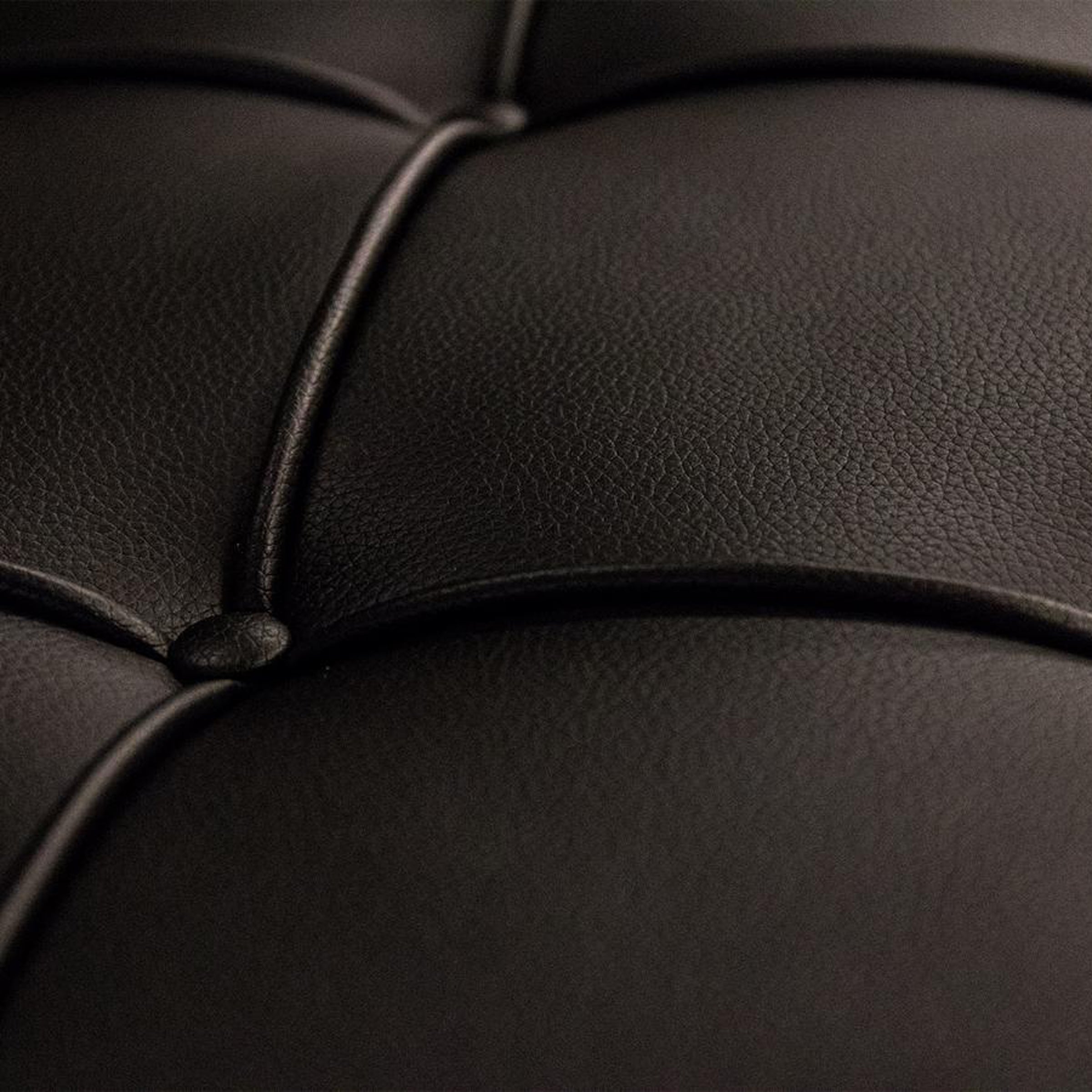 Nahaufnahme der schwarzen Lederpolsterung des Barcelona Hockers mit typischer Knopfsteppung