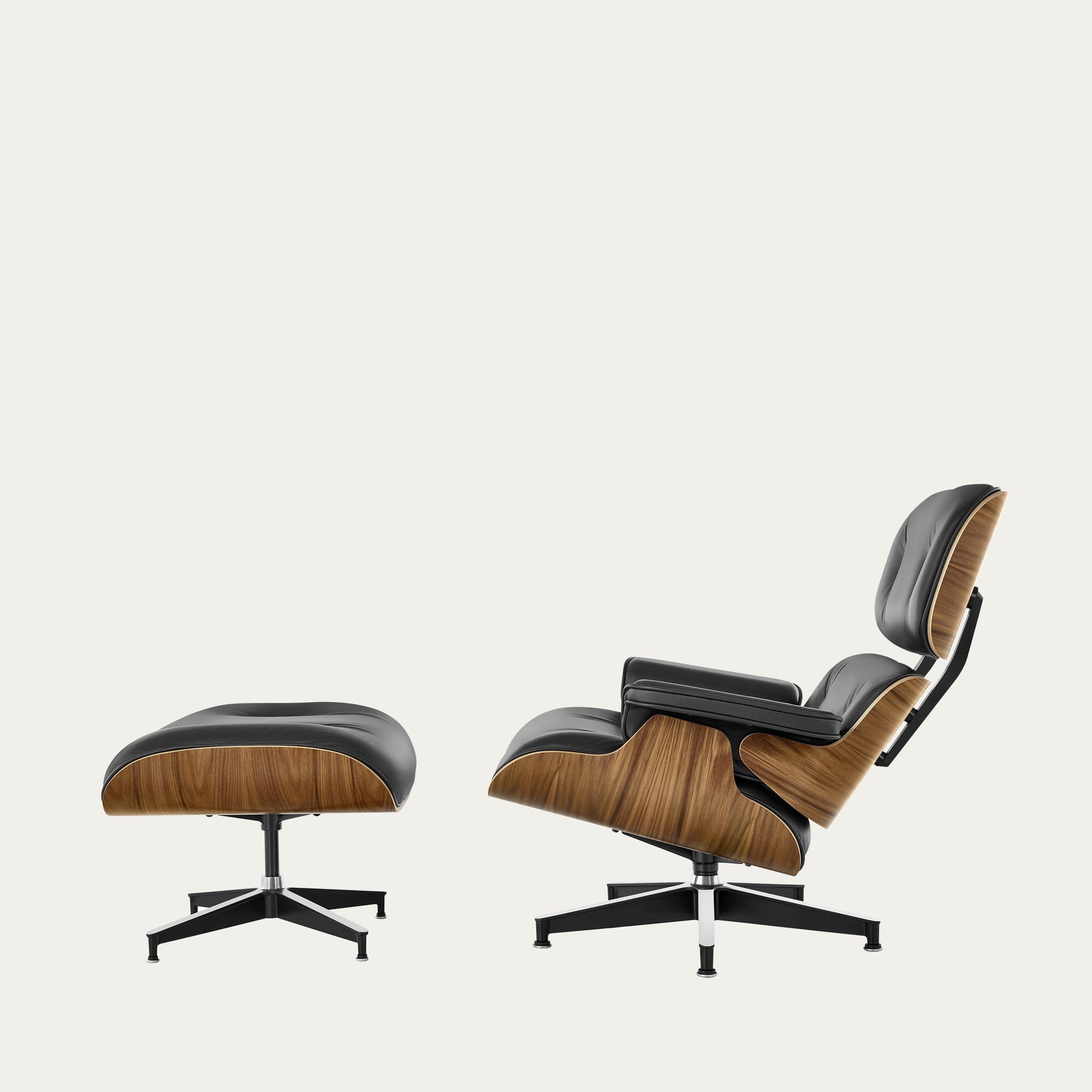 Seitenansicht des Eames Lounge Chair mit Ottoman von Charles & Ray Eames mit Nussbaumholz-Schalen und schwarzem Leder