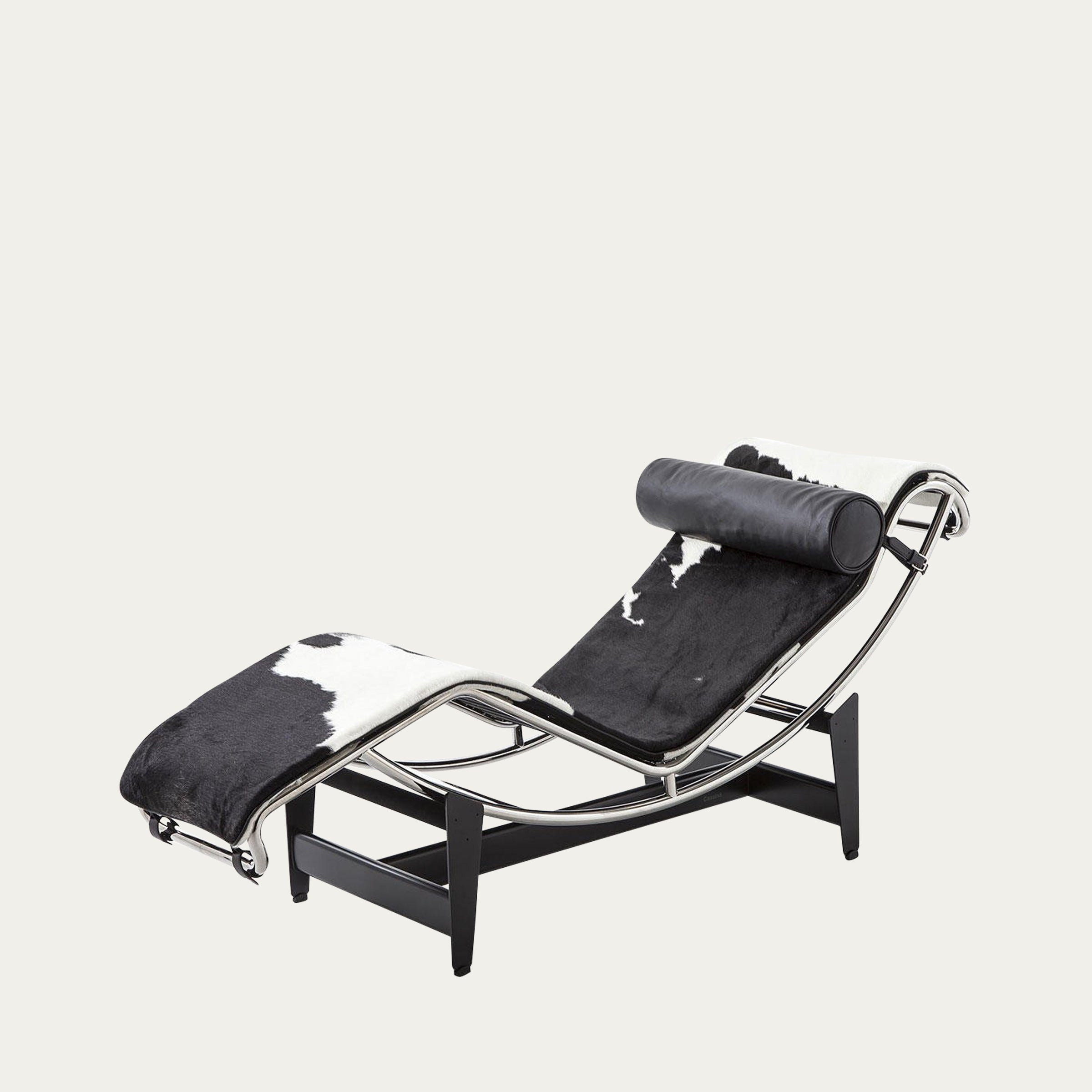 Perspektivansicht der LC4 Chaise Longue von Le Corbusier mit schwarz-weißem Kuhfellbezug und Lederkopfrolle