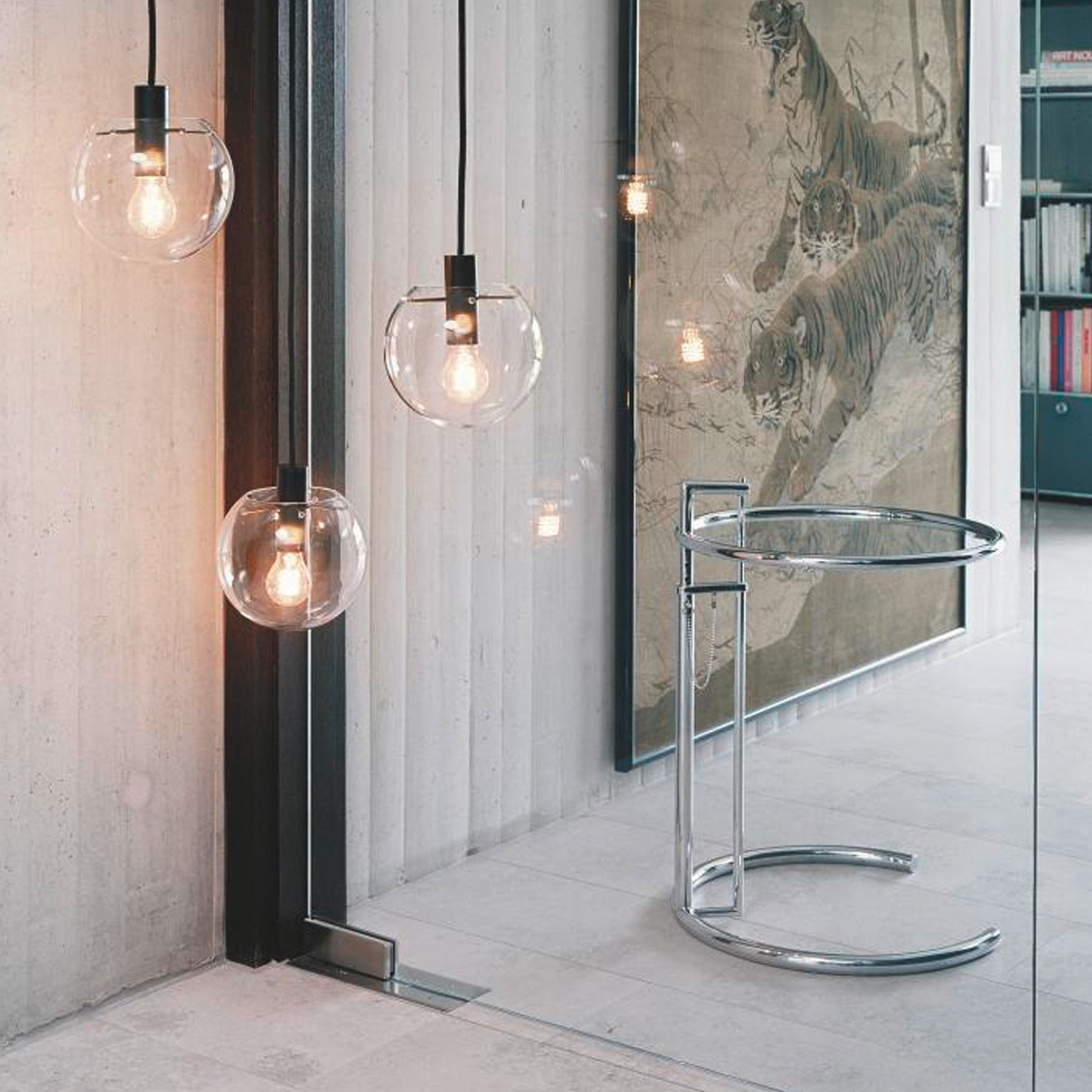 E1027 Beistelltisch von Eileen Gray aus verchromtem Stahl mit Glasplatte in modernem Wohnraum