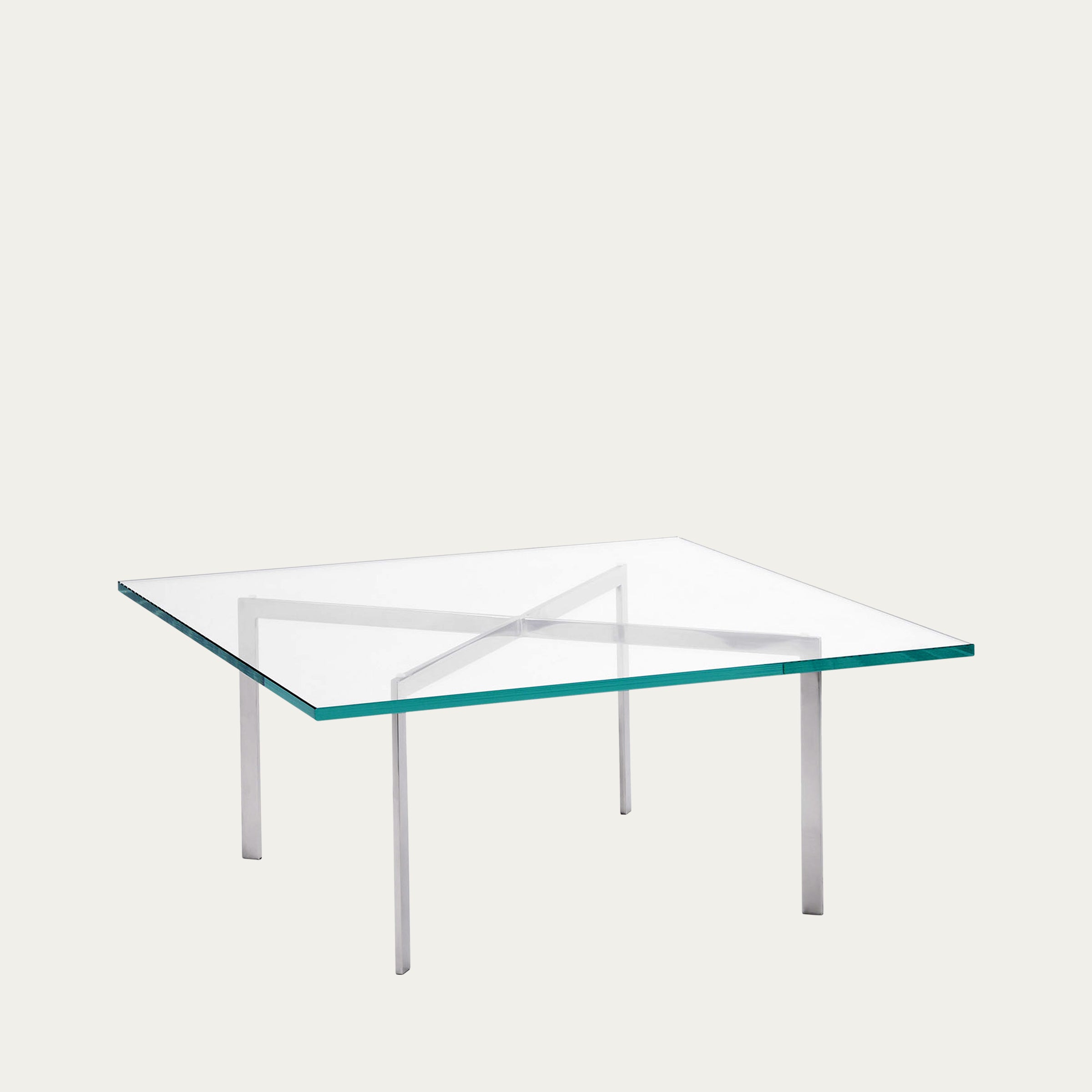 Quadratischer Barcelona Tisch mit klarer Glasplatte und kreuzförmigem Gestell aus poliertem Chromstahl, seitliche Perspektive.