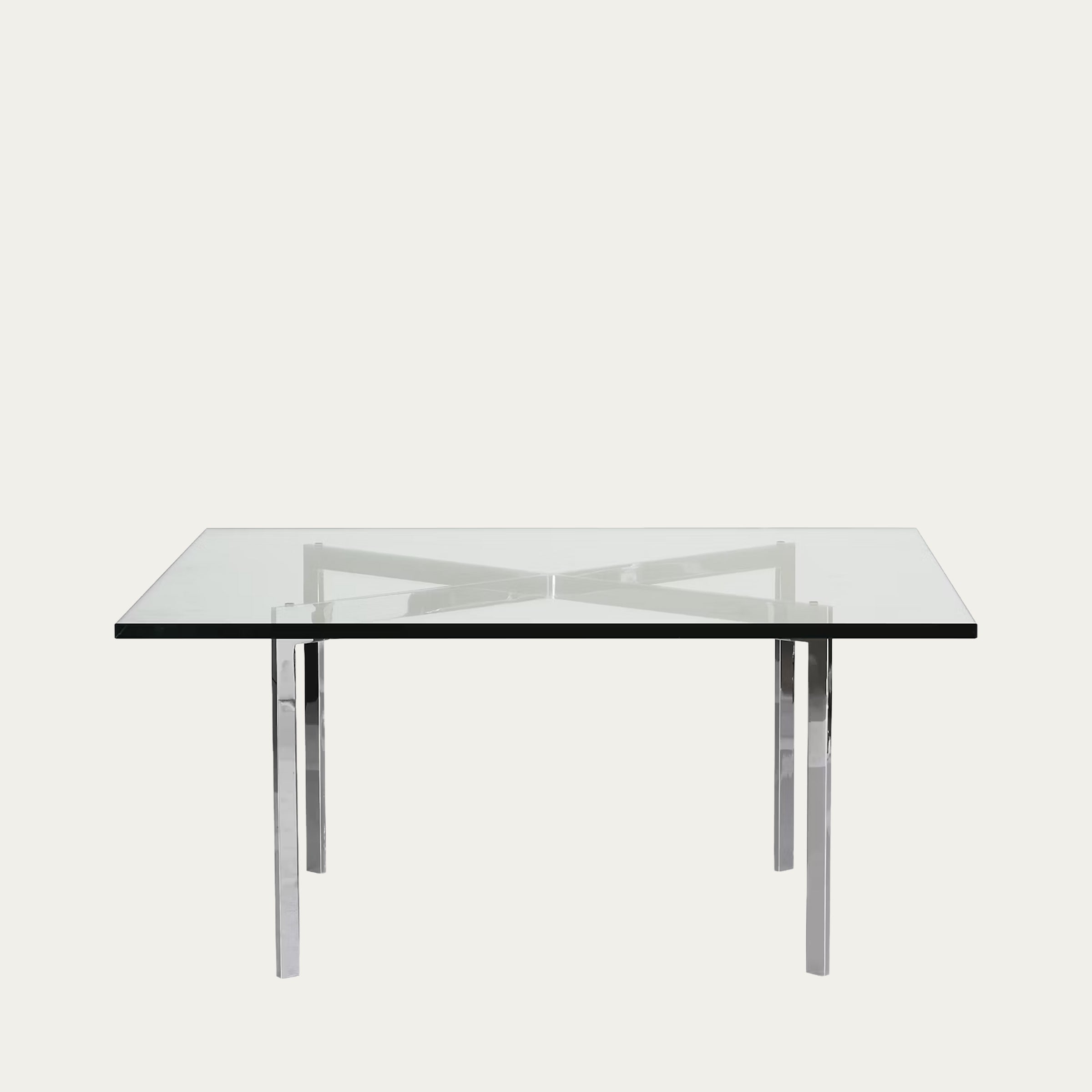 Moderne Ausführung des Barcelona Tisches mit dicker Glasplatte und schlankem, reflektierenden Chromgestell in Vorderansicht.