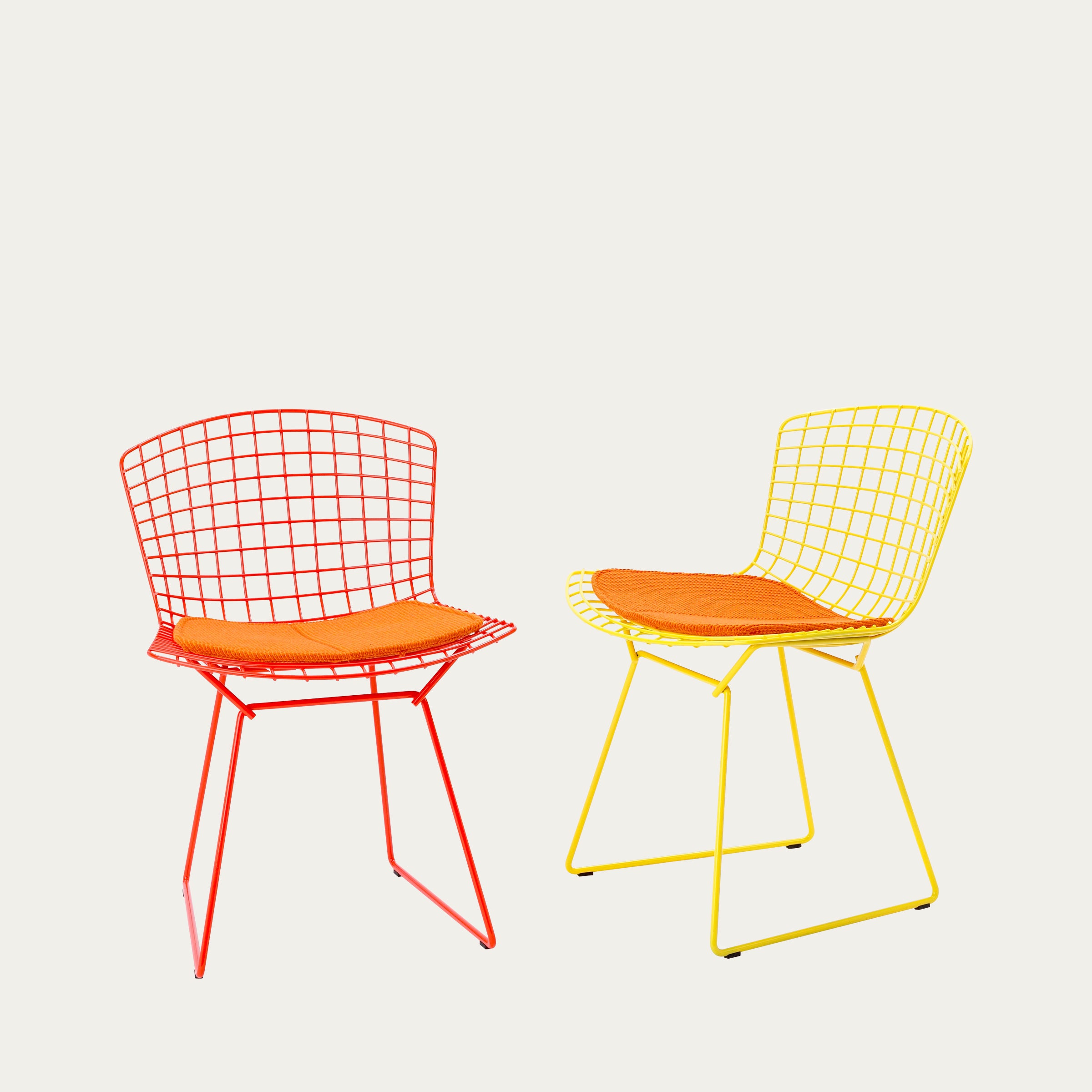 Zwei Bertoia Side Chairs von Harry Bertoia aus Drahtgeflecht in Rot und Gelb mit orangefarbenen Sitzpolstern