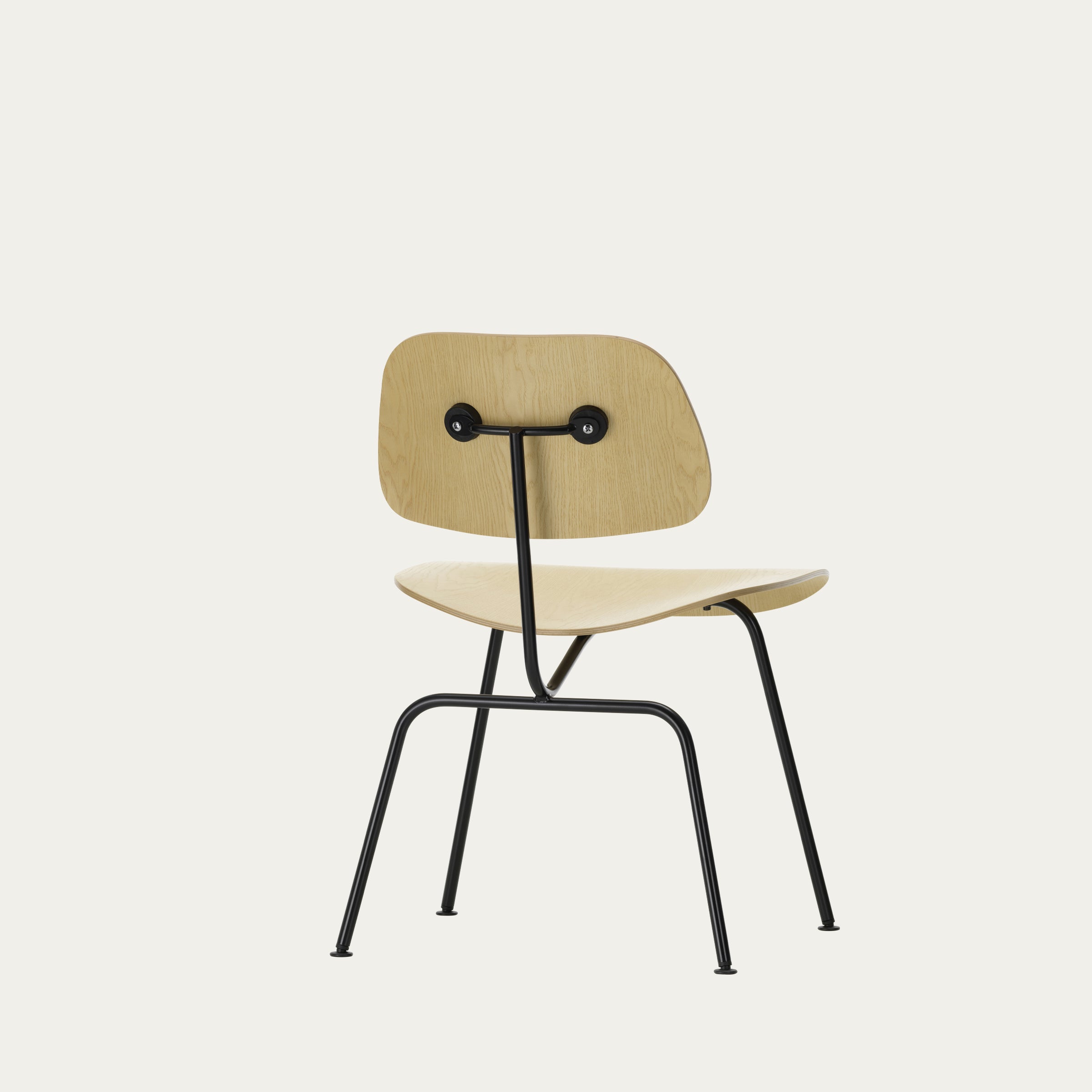 Rückansicht des DCM Stuhls von Charles & Ray Eames mit sichtbar verschraubter Holzrückenlehne und schwarzem Metallrahmen