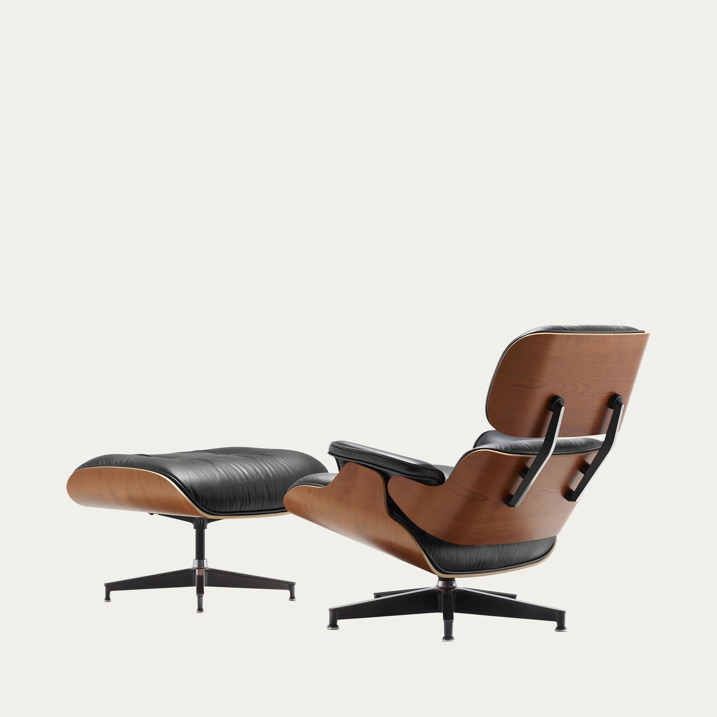 Schräg von hinten fotografierter Eames Lounge Chair mit Ottoman von Charles & Ray Eames in dunkler Holz-Ausführung