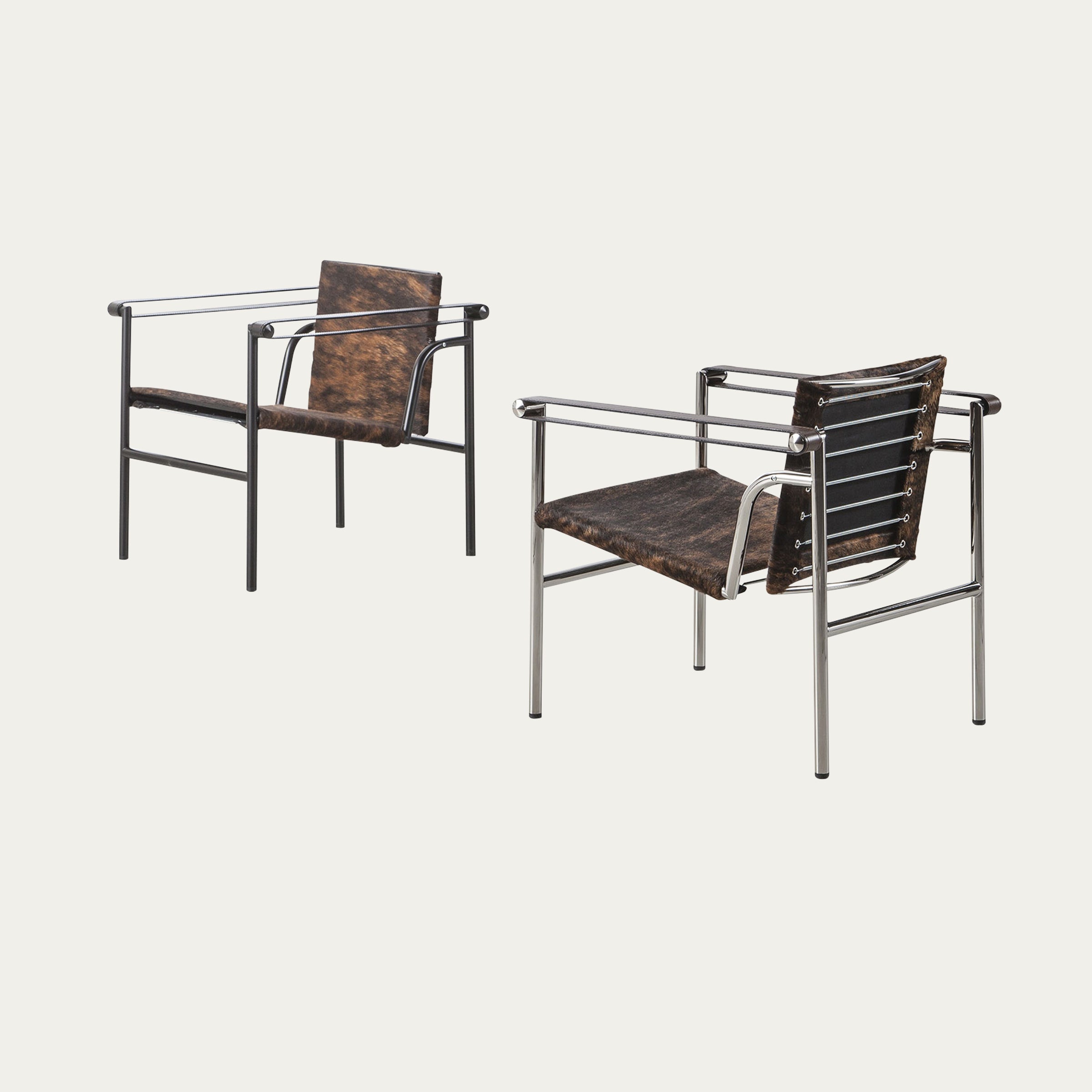 Zwei LC1 Sessel von Le Corbusier in Kuhfelloptik, einer mit verchromtem Rahmen, der andere mit schwarzem Stahlrahmen